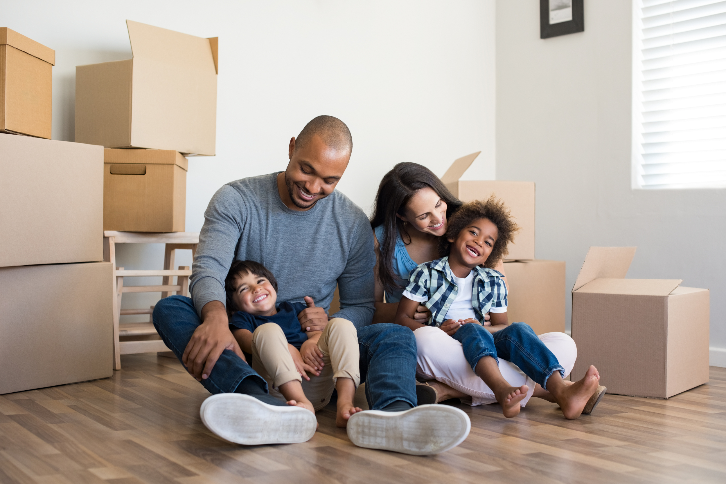 Young family sitting in a new home surrounded by boxes